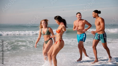 Group of young couples in swimwear having fun on summer vacation running along beach and splashing each other in waves in South Africa - shot in slow motion