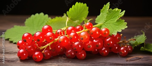 A collection of vibrant red berries  known as red currants  are arranged neatly on top of a rustic wooden table. The berries are surrounded by green leaves  creating a visually appealing and natural
