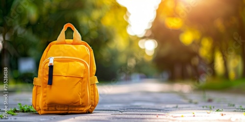 Vibrant yellow backpack on a sun-drenched park pathway signaling outdoor adventure. photo