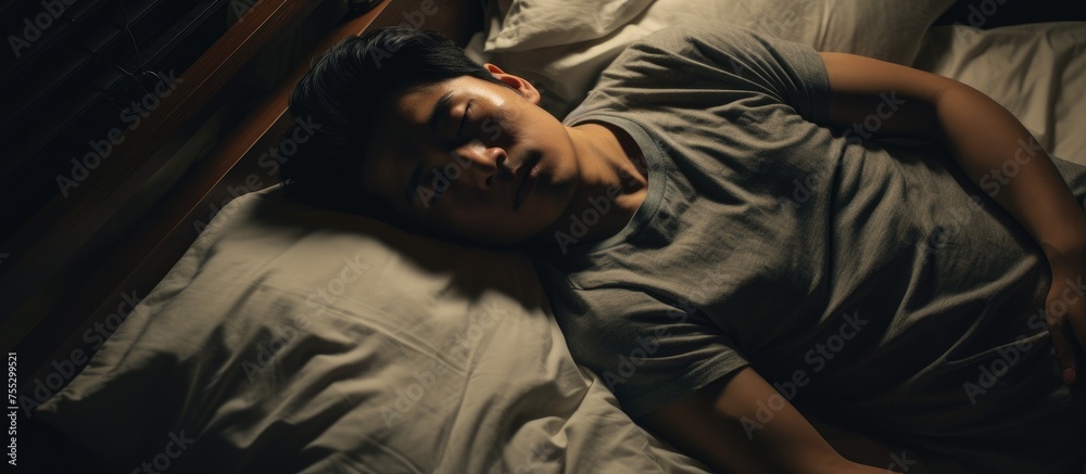 An Asian man, unable to sleep due to depression, lies in bed with his head resting on the pillow. His eyes are wide open, indicating the struggle he faces with insomnia. An Asian man, unable to sleep due to depression, lies in bed with his head resting on the pillow. His eyes are wide open, indicating the struggle he faces with insomnia.