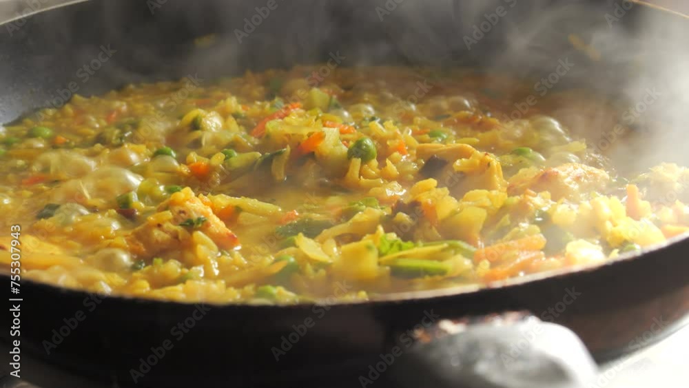 A large pan of bubbling risotto is boiling. Risotto with vegetables and pieces of chicken is prepared in the home kitchen A large pan of bubbling risotto is boiling. Risotto with vegetables and pieces of chicken is prepared in the home kitchen