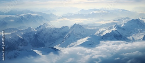 From above, the Caucasus Mountains are blanketed in snow, creating a stunning contrast with the dark shadows cast by passing clouds. The rugged peaks stretch as far as the eye can see, showcasing the