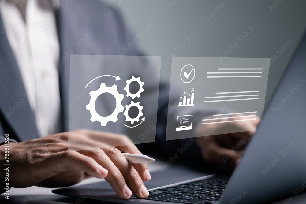 Automation concept. Businessman using laptop with automation icon on virtual screen for automated business process workflow optimization. Automation concept. Businessman using laptop with automation icon on virtual screen for automated business process workflow optimization.