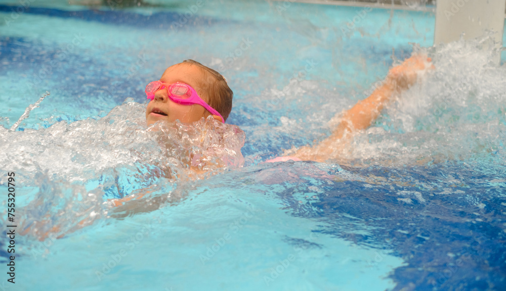 Child diving in swimming pool. Toddler kid jumping into the water in goggles learning to swim. Girl having fun in water, splashing in aquapark