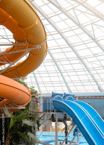 Aquapark with water rides. Indoor water park for entertainment. Nobody. Water slides under roof with green palm trees all year around 