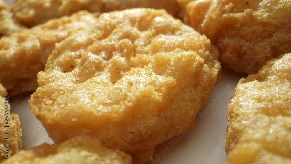 A chicken nugget is a small piece of chicken, either ground or whole, coated in batter or breadcrumbs, then deep-fried or baked until crispy. Shot with 24mm probe macro lens. Fast-food background. 4K. A chicken nugget is a small piece of chicken, either ground or whole, coated in batter or breadcrumbs, then deep-fried or baked until crispy. Shot with 24mm probe macro lens. Fast-food background. 4K.