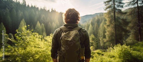 A young man with a backpack is seen walking through a dense forest. The traveler appears happy and engaged in his surroundings, embodying a sense of wellness and holistic rest.