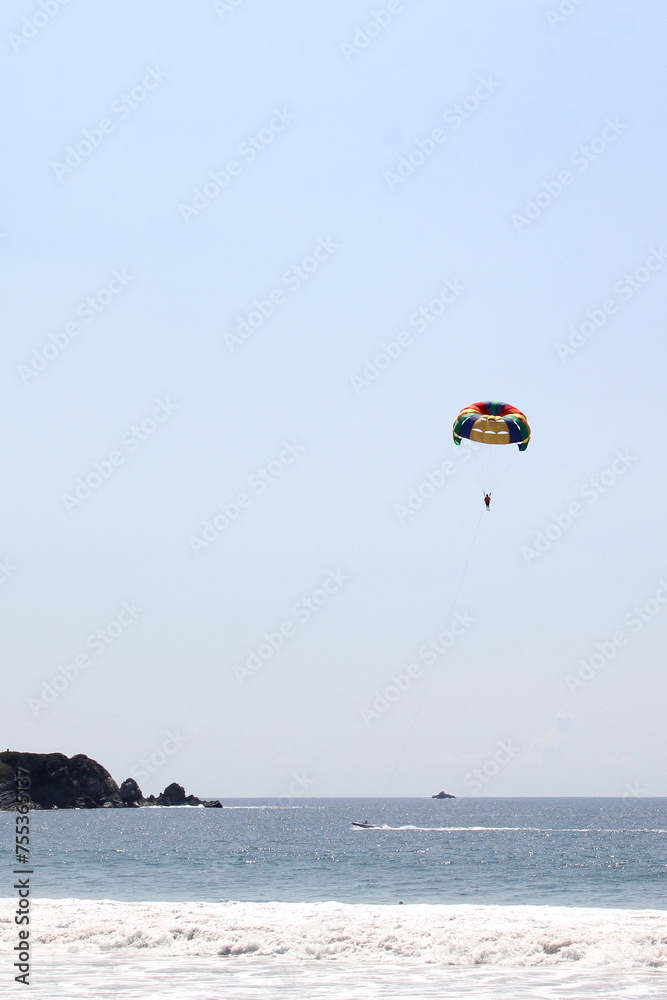 Parasailing, Parascending or Parakiting is an aquatic activity where a person attached to a parachute is towed by a boat at speed, causing them to rise above the water Parasailing, Parascending or Parakiting is an aquatic activity where a person attached to a parachute is towed by a boat at speed, causing them to rise above the water