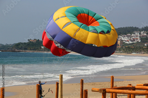 Parasailing, Parascending or Parakiting is an aquatic activity where a person attached to a parachute is towed by a boat at speed, causing them to rise above the water photo