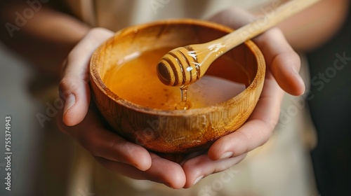 Female hands holding a bowl of bee honey and a wooden spoon. Close up.
