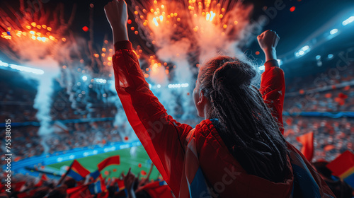 Excited Female Fan Cheering at Stadium During Night Match with Fireworks