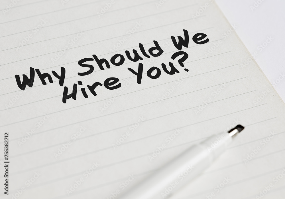 The business interview question of why should we hire you written on a notebook with pen marker.