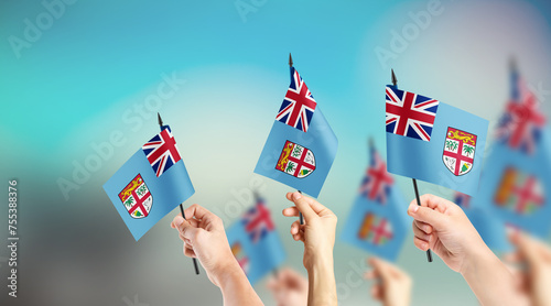 A group of people are holding small flags of Fiji and Tobago in their hands. photo