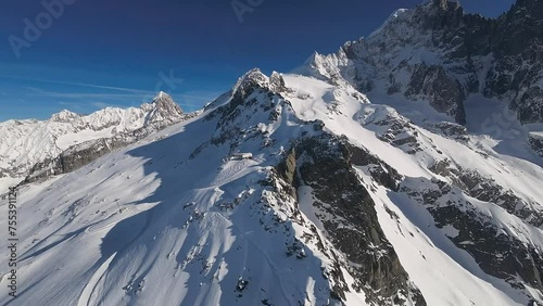 Stunning aerial view of the snow-draped ridges of Chamonix with ski tracks etched into the pristine white slopes. Sunny winter day in French Alps with snowy mountain peaks, Chamonix ski resort.