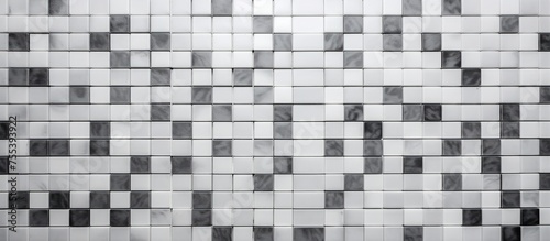 A monochromatic tiled wall featuring a pattern of white mosaic tiles on a grey square texture background, exuding a sense of luxury and elegance.