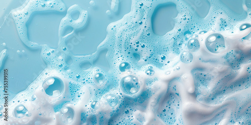 Abstract white soap foam bubbles on blue background. Soapy liquid texture with bubbles. Skin care cleansing cosmetic in top view.