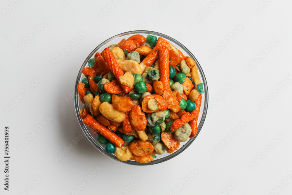 Mixed peanut and snacks, on transparent glass bowl, isolated on white background, flat lay or top view