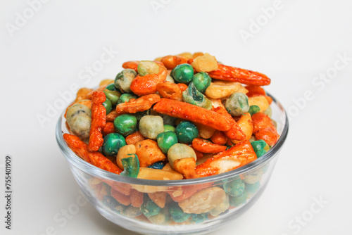 Mixed peanut and snacks, on transparent glass bowl, isolated on white background