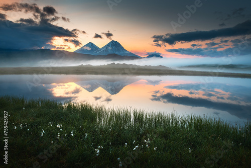 Volcanoes and their reflections in the lake at sunrise in Kamchatka, Russia. Klyuchevskoy Nature park