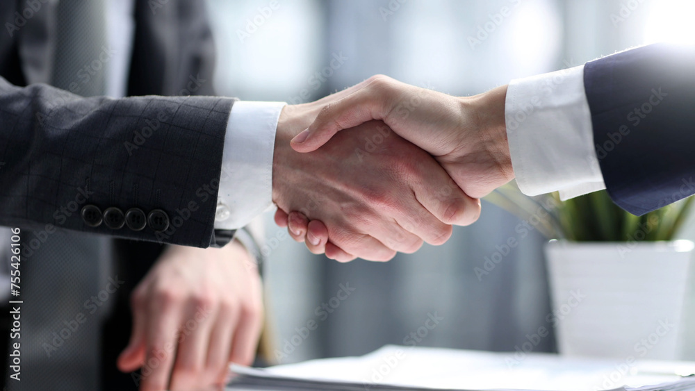 Businessmen shake hands in close-up in the office