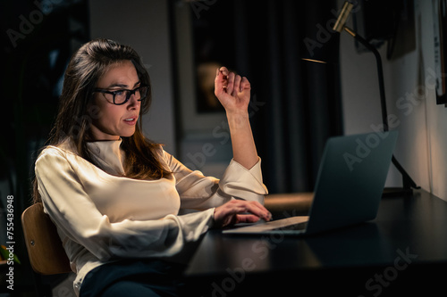 Woman using laptop having online video call at home at night in dark room