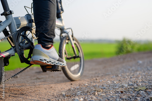 Closeup foot of the bicycle rider on the pedal while riding on the gravel and dirt road in countryside photo