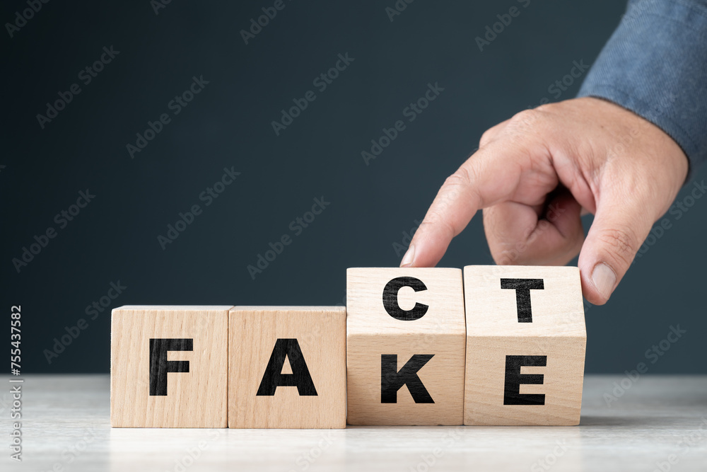 Naklejka premium Fact or Fake concept by alphabet wood cubes, with hand flip some blocks to change the different words