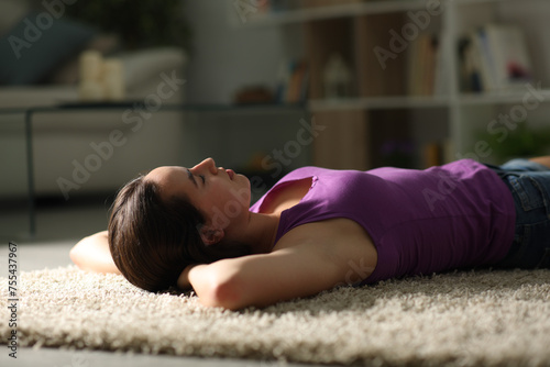 Woman relaxing lying on a carpet in the night