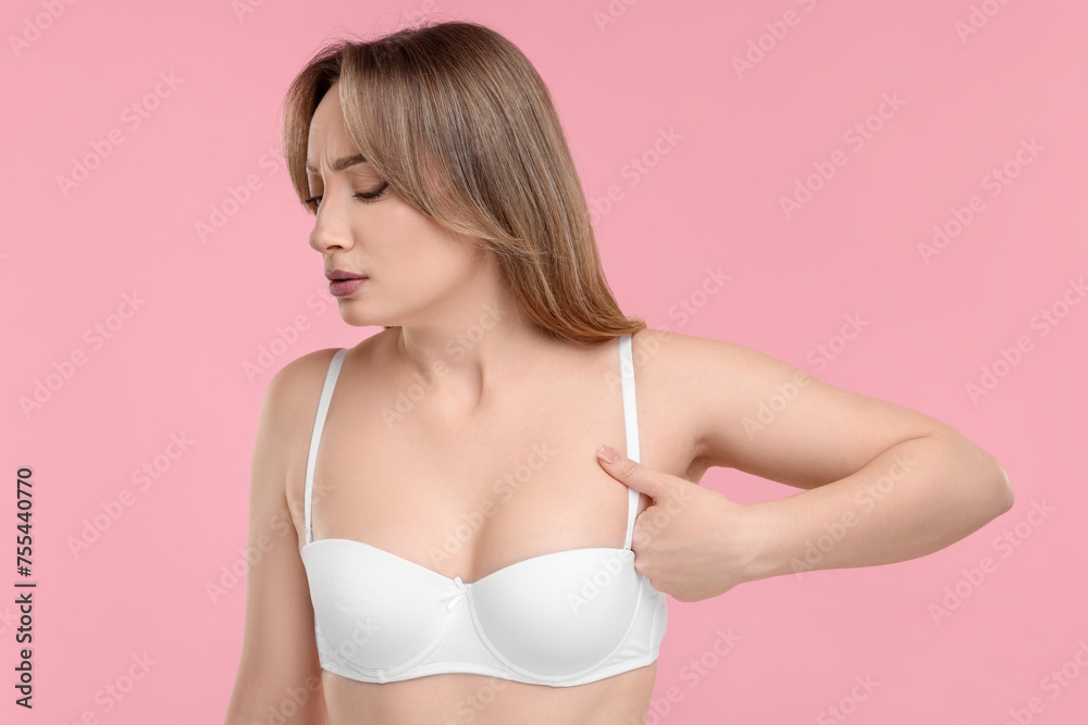 Obraz premium Mammology. Young woman doing breast self-examination on pink background