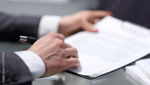 Businessman in close-up working at a desk in the office and signing a contract