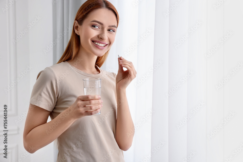 Beautiful young woman taking vitamin pill at home. Space for text Beautiful young woman taking vitamin pill at home. Space for text