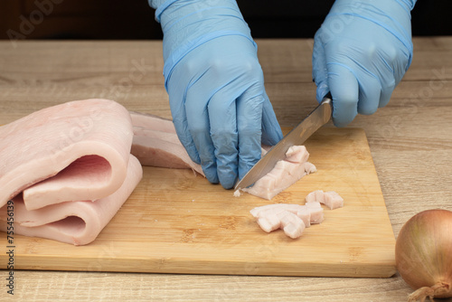 Fat is cut into small pieces. Hands of a cook cutting lard with a knife into small pieces to prepare food. home cuisine