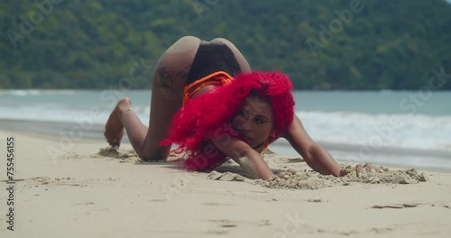 Amidst the pristine white sands of a Caribbean beach, a girl with red hair showcases her bikini. photo