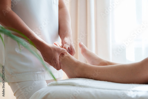 Osteopath treating pressure points on patient's foot in treatment room photo