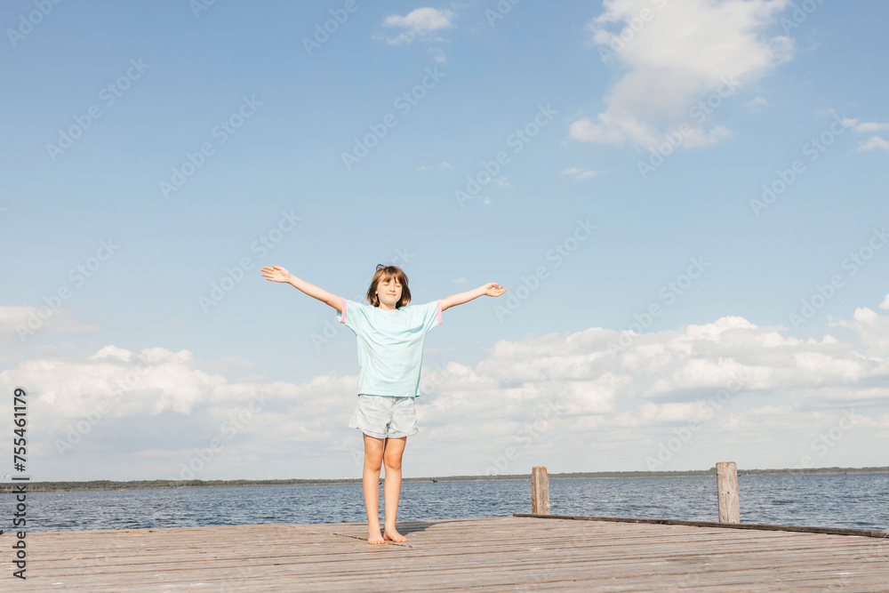 Girl standing with arms outstretched on wooden pier at lake Girl standing with arms outstretched on wooden pier at lake