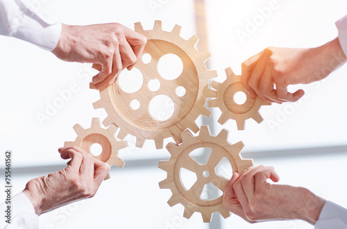 Hands of people office workers business partners making common picture of wooden gears on table