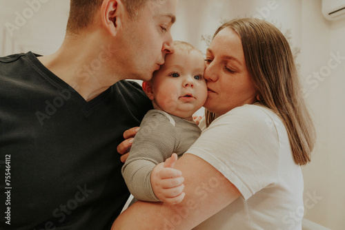 Parents kissing baby boy at home photo