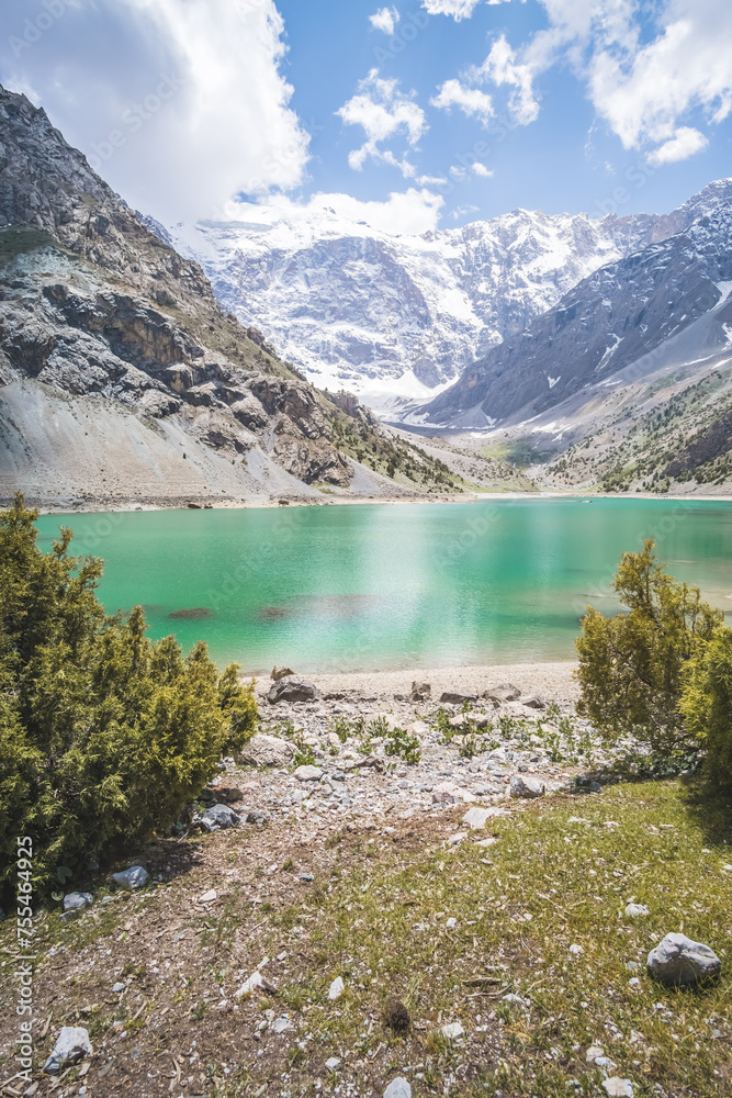 Obraz premium Blue lake Kulikalon against the backdrop of rocky mountains with glaciers in the Fan Mountains in Tajikistan, mountain panorama and turquoise lake