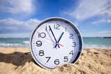 clock with time passing on a beach