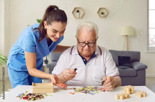Foto Nurse in geriatric clinic or retirement home helping patient with alphabet puzzle