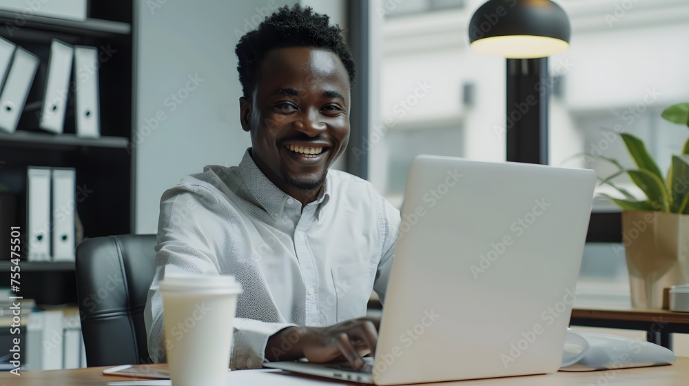 Smiling businessman in suit sitting using a laptop in a comfortable workplace, office. looking at camera, front side view. Smiling businessman in suit sitting using a laptop in a comfortable workplace, office. looking at camera, front side view.