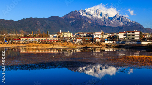 A small town under Jade Dragon Snow Mountain and the reflection of the snow mountain