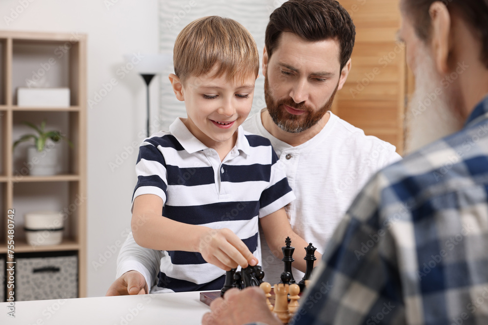 Family playing chess together at table in room Family playing chess together at table in room