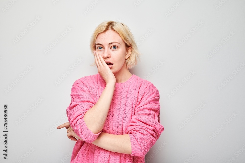 Surprised young woman in pink blouse with hand on cheek, white background. Surprised young woman in pink blouse with hand on cheek, white background.