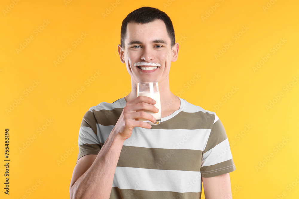 Happy man with milk mustache holding glass of tasty dairy drink on orange background - obrazy, fototapety, plakaty 