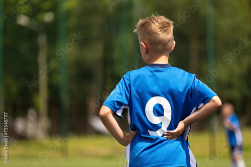 Boy playing soccer with teammates. The soccer boy plays as a forward. Kids soccer team in a soccer league match. A child in a blue football uniform with the number nine on back