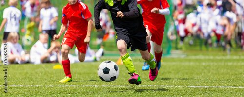 Fototapeta Naklejka Na Ścianę i Meble -  Group of Children Playing Soccer Football League Game. A Player Running Fast With a Soccer Ball Toward the Goal Ready To Kick the Ball and Score. Kids Compete in a Football Tournament on a Grass Pitch