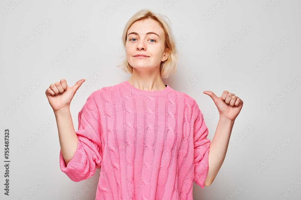 Confident woman in pink sweater pointing at herself with thumbs, isolated on white background. Confident woman in pink sweater pointing at herself with thumbs, isolated on white background.