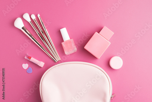 Make-up cosmetic bag on pink background. Glamour makeup pouch and beauty products from above.