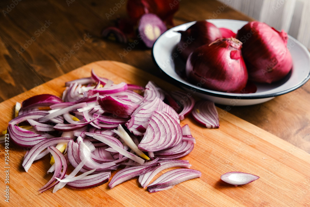 Board and bowl with pieces of fresh red onion on wooden background